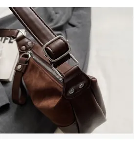 Detail of premium brown suede saddle bag featuring silver metallic hardware and rivets