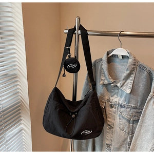 Dettaglio borsa a mezzaluna in nylon nero con mini portamonete tondo e logo del brand