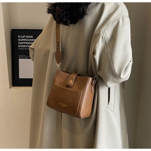 Detail of brown leather bucket bag with jacquard strap and gold fashion logo