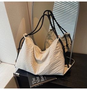 Detail of checkered hobo bag with Fashion embroidery and rope knot strap on books