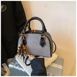 Detail of grey suede and black leather Boston bag with beaded tassel and gold hardware
