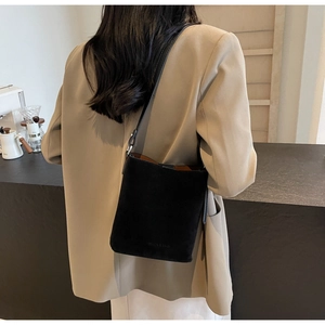 Detail of a black suede bucket bag with FASHION & BAGS embossing and a brown lining