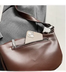 Detail view of the front zipper pocket on a brown leather bag showing storage capacity