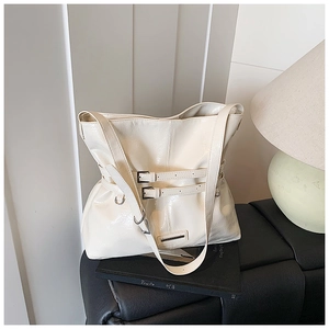 Dettaglio di una grande borsa tote bianco sporco in finta pelle con fibbie argentate e texture