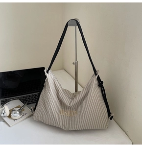 Detail of checkered tote bag with golden Fashion embroidery and sleek black shoulder strap