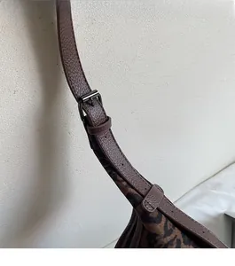 Detail showing the adjustable brown leather strap and buckle of the leopard tote bag