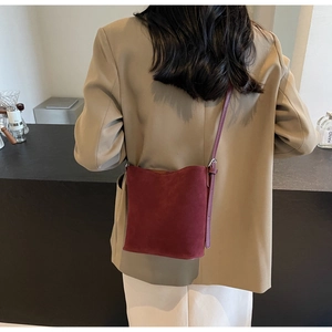 Close-up of deep red frosted bucket bag with embossed logo on soft suede leather