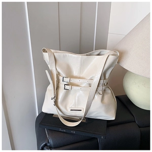 Dettaglio di una grande borsa tote crema in ecopelle lucida con cinturini decorativi
