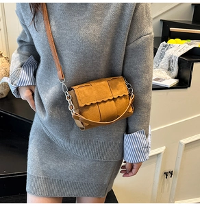 Detail of caramel brown woven leather crossbody bag with jagged edge and silver chain