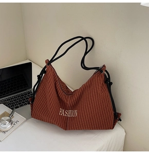 Brown plaid tote bag with rope handles and golden embroidery on a minimalist white desk