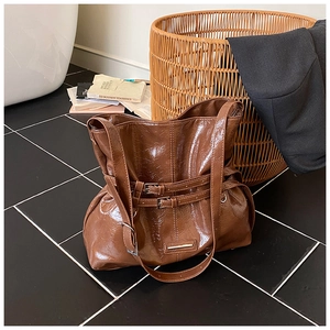 Dettaglio di una grande borsa tote marrone lucida con fibbie in metallo e stile vintage
