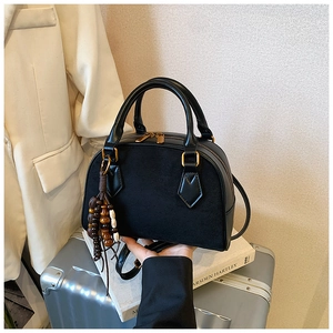 Detailed macro view of black patchwork pillow bag with elegant suede and gold hardware
