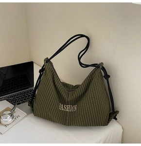 Close-up of olive green checkered canvas bag with gold FASHION embroidery and rope strap