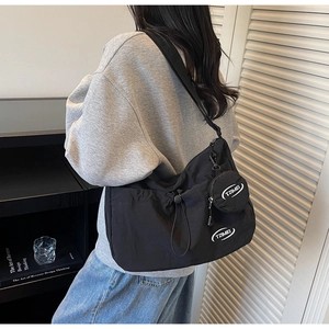 Dettaglio di una borsa a tracolla in nylon nero con coulisse e portamonete rotondo coordinato