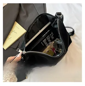 Interior view of black glossy shoulder bag showing large capacity for books and perfume