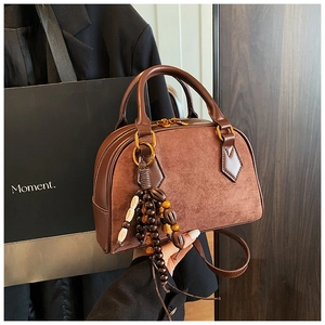 Macro view of dark brown suede Boston bag with leather patchwork and ethnic beaded tassel