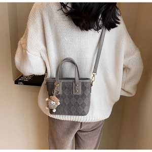 Close-up of frosted gray bucket bag with embossed patterns and pinecone plush charm