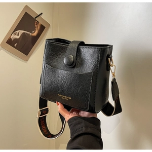 Détail du sac seau vintage noir avec texture craquelée et lettrage du logo doré