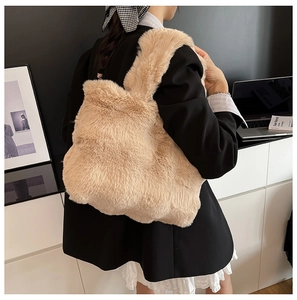Detailed view of plush tote bag in beige faux fur carried by a model in a modern office