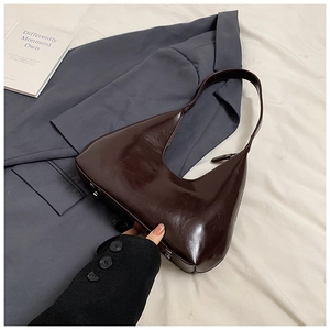 Détail de la texture brillante et de la fermeture éclair du sac hobo en cuir marron foncé