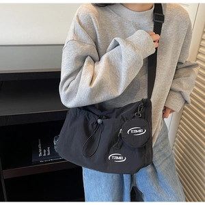 Dettaglio borsa a tracolla in nylon nero con chiusura a coulisse e mini portamonete rotondo
