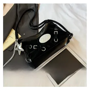 Detail of glossy black shoulder bag with silver hardware and large star pendant