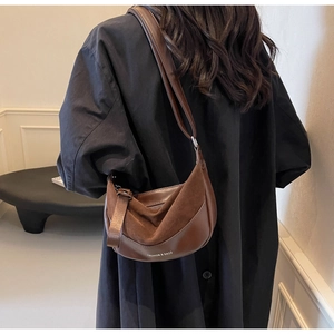 Detailed view of a brown suede and leather saddle bag featuring fashion lettering text