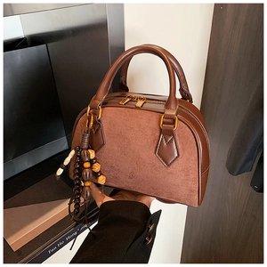 Close-up of vintage brown Boston bag featuring suede patchwork and wood bead tassels