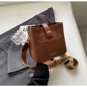 Gros plan d'un sac seau en cuir marron rétro avec bandoulière large en toile