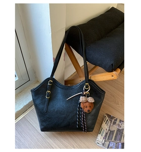 Detail der schwarzen Shopper-Tasche mit Retro-Ledertextur und süßem braunem Plüschbären