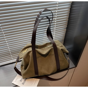 Detail of olive green canvas tote bag with brown leather straps and golden metal zipper