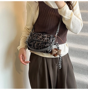 Detail of leopard print crossbody bag with plush bear charm and metallic ring buckle