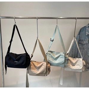 Group display of casual nylon messenger bags in black, khaki, light blue, and white colors