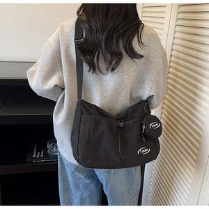 Vista posteriore della modella con borsa a tracolla in nylon nero e piccolo portamonete