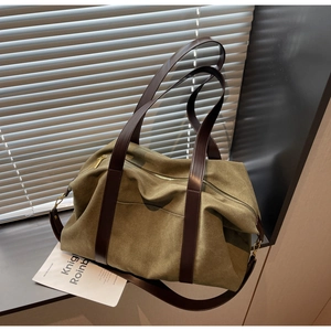 Detail of olive green suede tote bag showing brown leather handles and side hardware