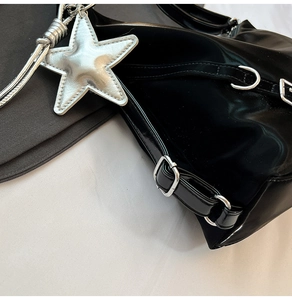 Detail of black patent leather bag with silver star charm and Y2K punk buckle straps