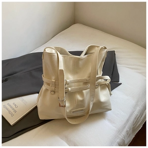Close-up of cream large tote bag with pleated texture and adjustable metal buckles detail