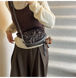 Detail of leopard print crossbody bag with wave flap and cute teddy bear charm
