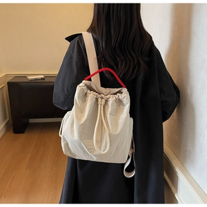 Dettaglio borsa a secchiello bianco sporco con manico intrecciato rosso e coulisse