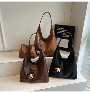 Detailed view of three large leather tote bags in brown and black with puppy pendants