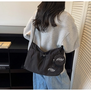 Dettaglio della borsa a tracolla in nylon nero con astuccio rotondo e logo TZIMEI