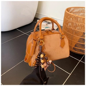 Detail of caramel brown Boston bag showing mixed leather textures and wooden bead tassel