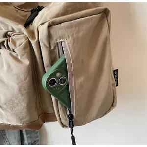 Dettaglio della tasca laterale con cerniera su una borsa a tracolla kaki e capienza