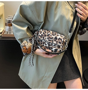 Close-up of leopard print woven crossbody bag with cute plush puppy charm and metal chain