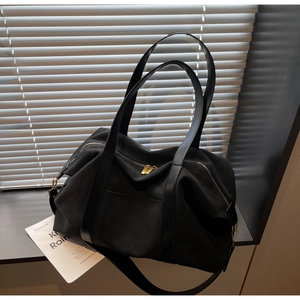 Detail of a large black canvas tote bag featuring gold zippers and premium fabric texture