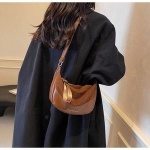 Detail view of retro brown half-moon saddle bag with minimalist leather texture and gold lettering