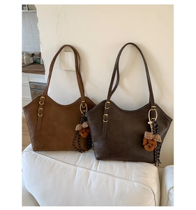 Detailansicht zweier Shopper aus Kunstleder in Brauntönen mit süßem Teddybär-Anhänger