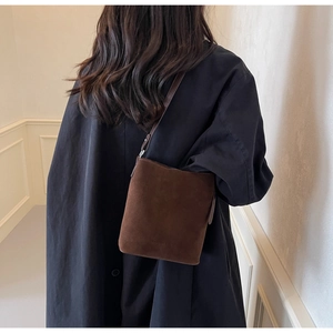 Detail of dark brown suede bucket bag with embossed Fashion & Bags text on shoulder strap