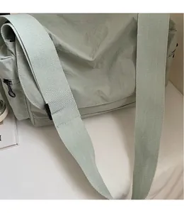 Close-up of light green nylon tote with wide strap and YOU JI BEAR logo detail