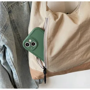 Dettaglio della tasca con cerniera di una borsa a tracolla in nylon beige con smartphone